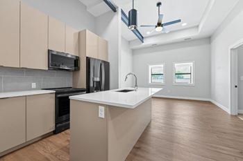 A modern kitchen with wooden floors and beige cabinets.